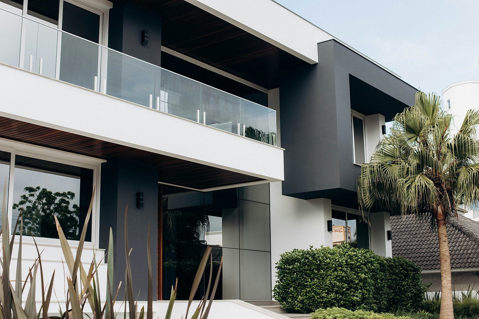 Contemporary villa exterior with glass balcony and landscaped entrance — representational imagery